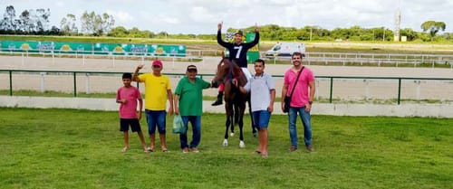 Jóquei de pé na sela comemora a vitória com a equipe no gramado